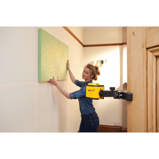STANLEY STHT1-77340 laser level device mounted on door, projecting lines for precise picture hanging.