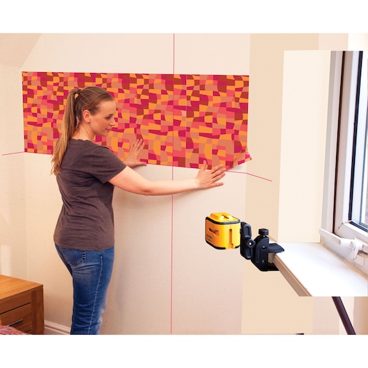 STANLEY STHT1-77340 laser level used for wallpaper alignment, side angle, photography indoor setting.