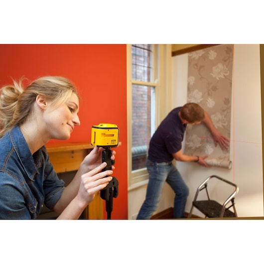 STANLEY STHT1-77340 laser level used for wallpaper alignment, photography showing tool in home setting.