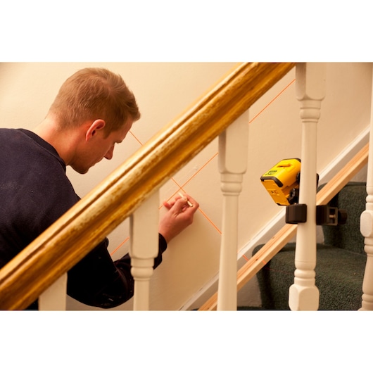 STANLEY STHT1-77340 laser level projecting lines on staircase wall, person marking alignment.