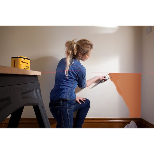 STANLEY STHT1-77340 photography of yellow laser level projecting lines on wall during painting.