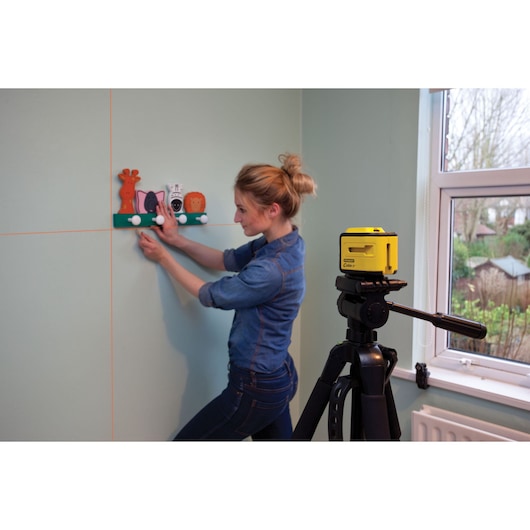 STANLEY STHT1-77340 photography of yellow laser level on tripod used for wall alignment indoors.