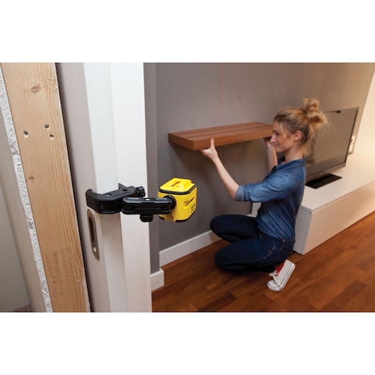 STANLEY STHT1-77340 yellow laser level in use for shelf alignment, photography category, side angle.