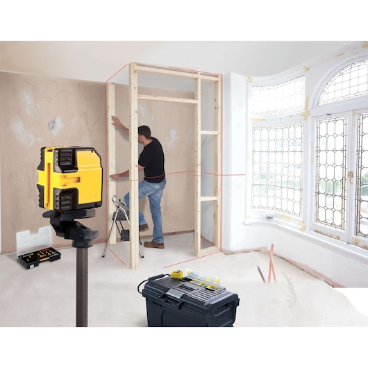 STANLEY STHT1-77341 laser level being used for wall framing, photography of workspace with tools.
