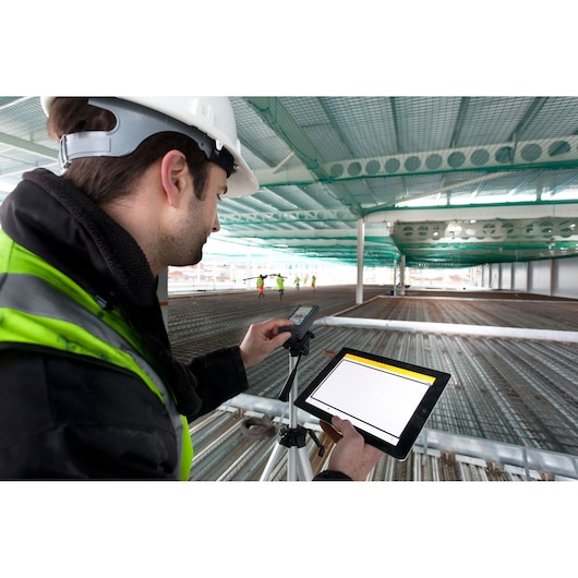 STANLEY STHT1-77347 photography of worker using laser distance meter and tablet on construction site.