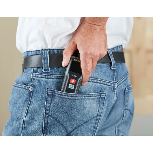 STANLEY STHT1-77354 digital laser measurer in hand, shown being placed in a jeans back pocket.