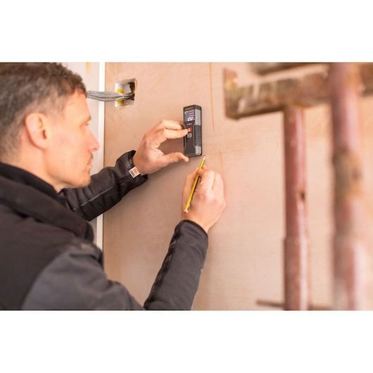 Photo of STANLEY STHT1-77354 laser distance measurer in use on a wall during construction.