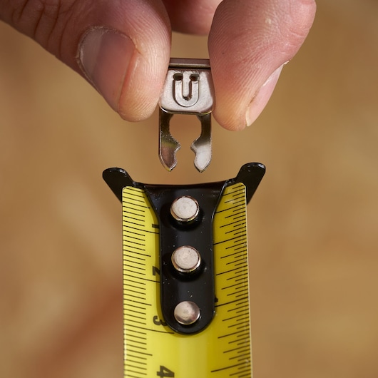 STANLEY STHT37235 tape measure close-up, yellow blade, black hook, top view, showing attachment feature.