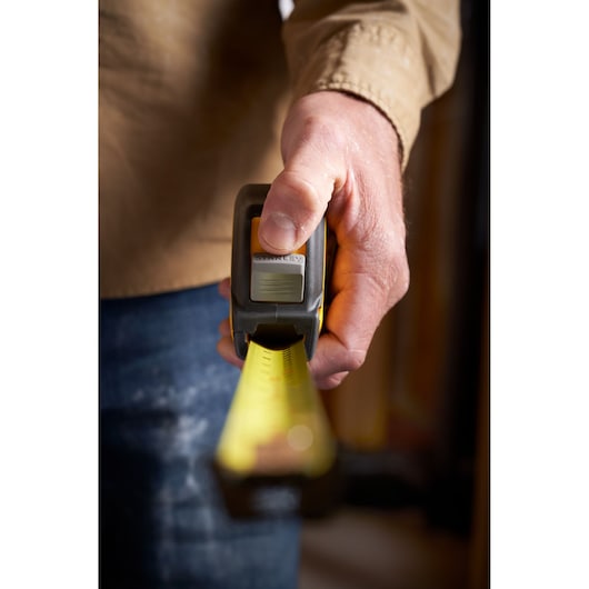 STANLEY STHT37237 tape measure held in hand, yellow blade extended, close-up photo.