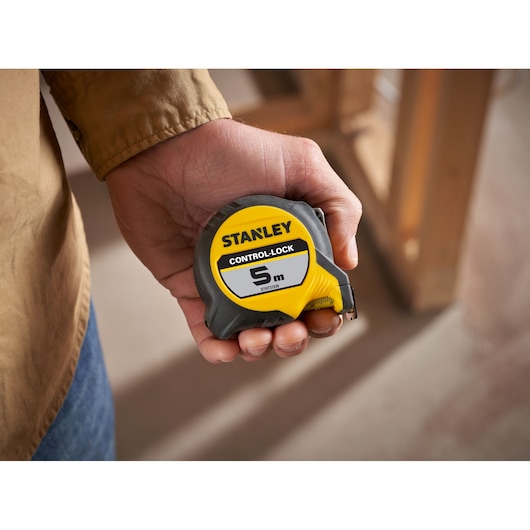 Photo of STANLEY STHT37239 tape measure, yellow and gray, 5m length, held in hand, product category: Photography.