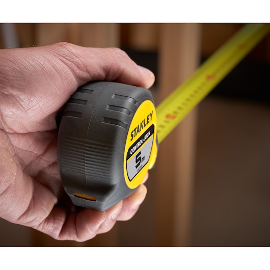 Photo of STANLEY STHT37239 tape measure, 5m, yellow and black, held in hand during use.