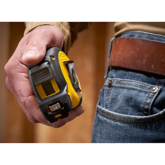 Photo of STANLEY STHT37240 tape measure in hand next to jeans and leather belt.