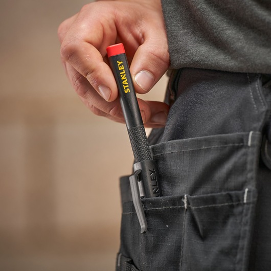 Hand placing a black STANLEY marker with red cap into a pocket on dark work trousers.