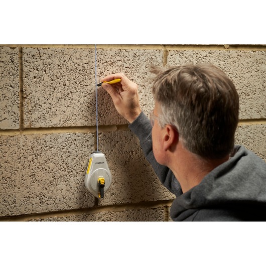 STANLEY STHT47110-0 chalk line reel used on a concrete wall with person marking a straight line.