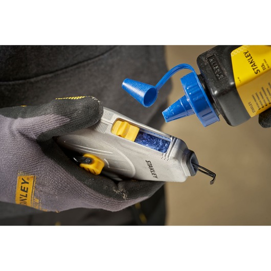 STANLEY STHT47110-0 chalk line tool being refilled with blue chalk powder, close-up view.