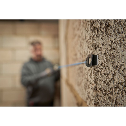 STANLEY STHT47110-0 chalk line tool in use against textured wall, close-up photography.