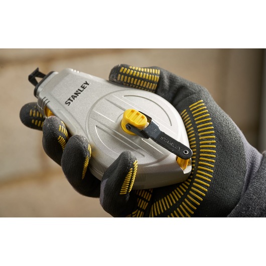 STANLEY STHT47110-0 chalk reel in silver and yellow held in gloved hand, photography close-up.
