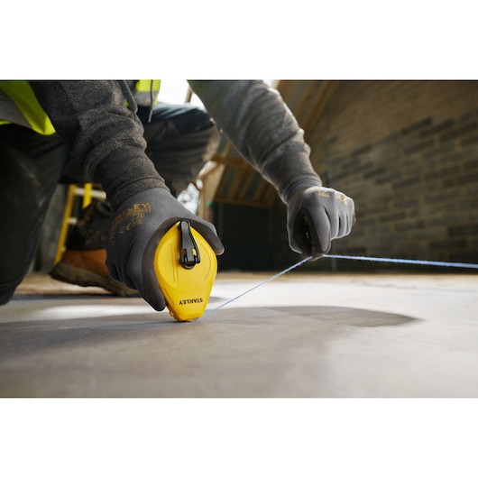 Photo of STANLEY STHT47112-0 chalk line tool in use on construction site floor.