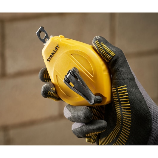 STANLEY STHT47112-0 chalk line tool with yellow casing, photographed in a gloved hand, close-up view.