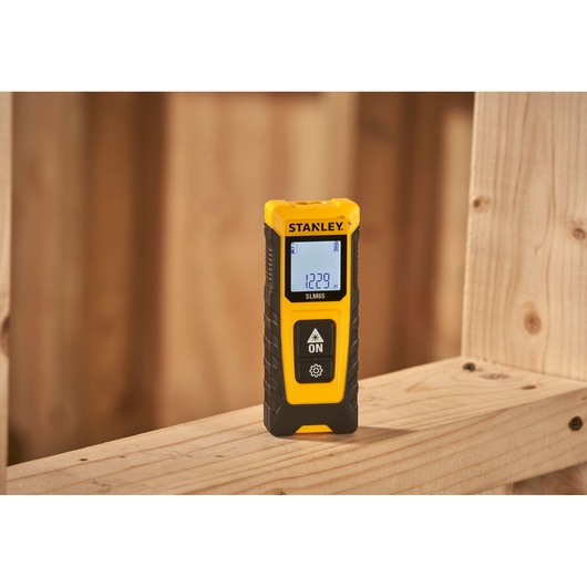 STANLEY STHT77065-0 laser distance measurer with digital display on wooden beam, photography category.