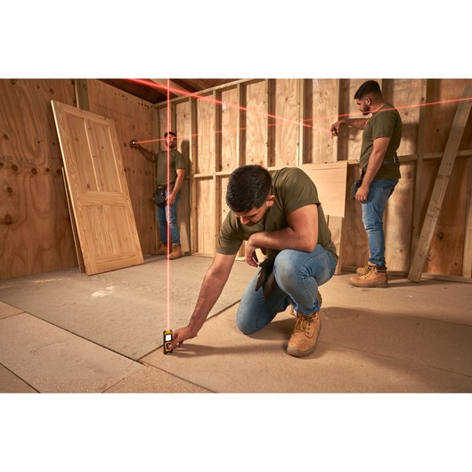 STANLEY STHT77100-0 laser level in use on construction site by workers, projecting red alignment lines.