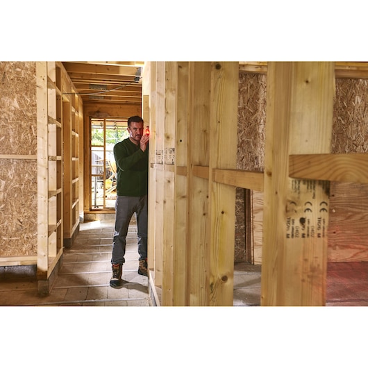 STANLEY STHT77666-0 laser level in use for wall alignment in wooden framed construction site.