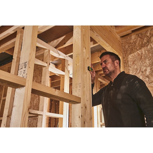 STANLEY STHT77666-0 laser distance measurer in use during wall framing construction.