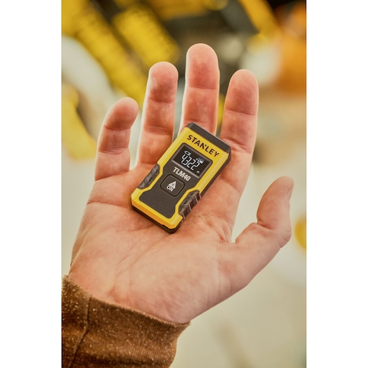 Photo of STANLEY STHT77666-0 TLM40 laser distance measurer held in hand, displaying digital screen.