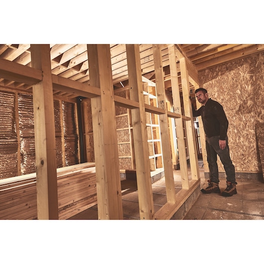 STANLEY STHT77666-0 photography of worker inspecting wooden framework in unfinished construction site.