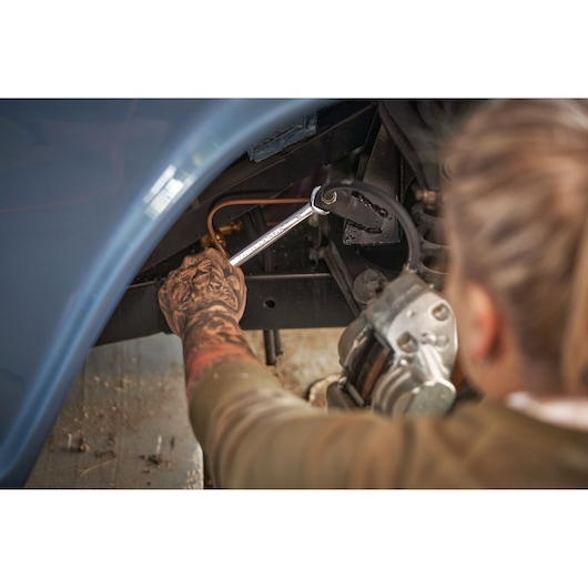 STANLEY STMT82832-1 ratchet wrench in use repairing a car, user holding tool under car wheel well.