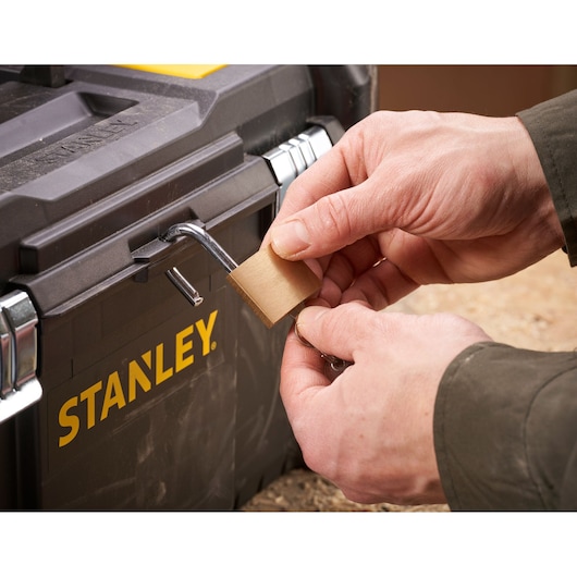 Photo of STANLEY STST1-75521 toolbox being secured with a padlock, close-up on locking action.