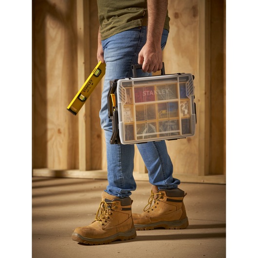 STANLEY STST1-75540 plastic organizer with clear lid and black handle, carried by a person wearing work boots.