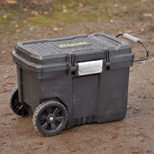 STANLEY STST33090-1 rolling black tool box with wheels and handle, wet outdoors.