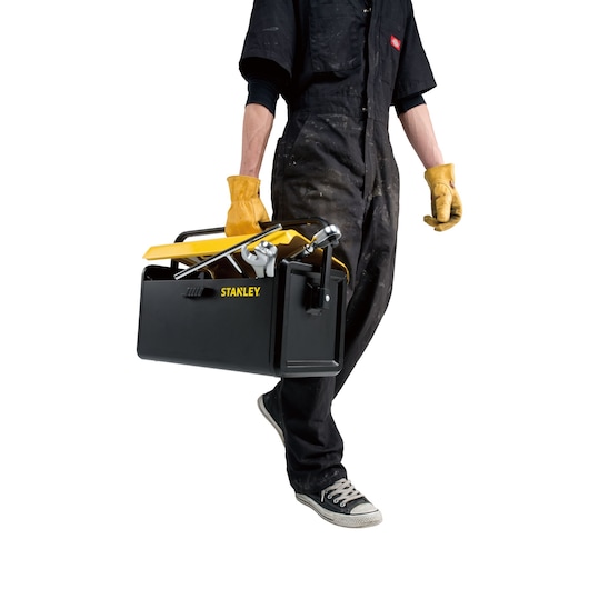 Photo of a person carrying a STANLEY STST73099-8 black and yellow metal toolbox with handle, front view.
