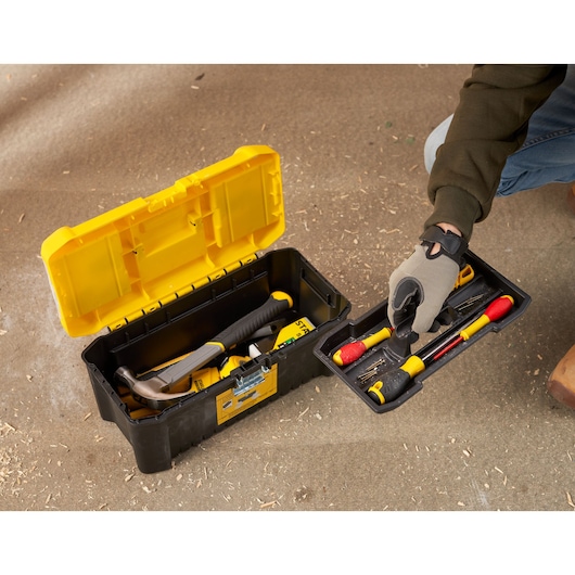 STANLEY STST75785-1 tool box with open lid, showing hand lifting tray with assorted hand tools on workshop floor.