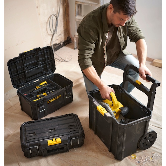 Photo of STANLEY STST83319-1 stackable tool boxes with yellow latches, including one wheeled box, in a workshop setting.