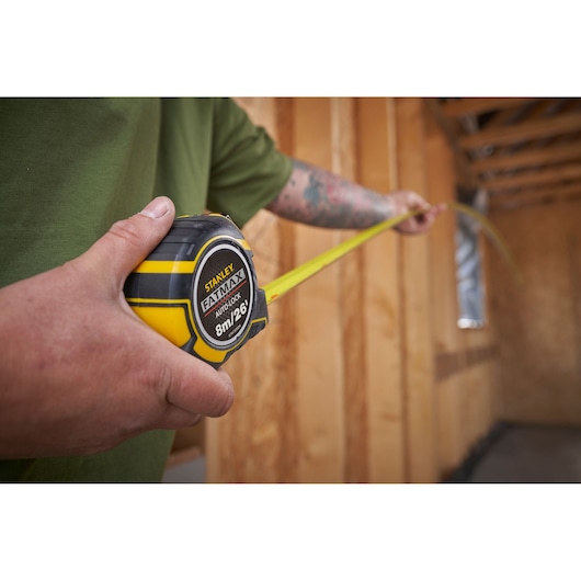 Photo of STANLEY XTHT0-33504 tape measure, 8m/26ft, in use at a construction site.